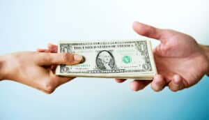 One person hands a stack of cash to another person.