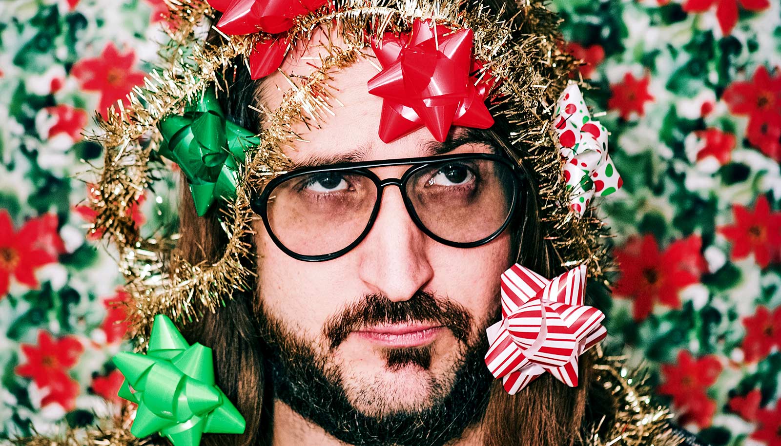 A man looks frustrated covered in holiday gift bows.