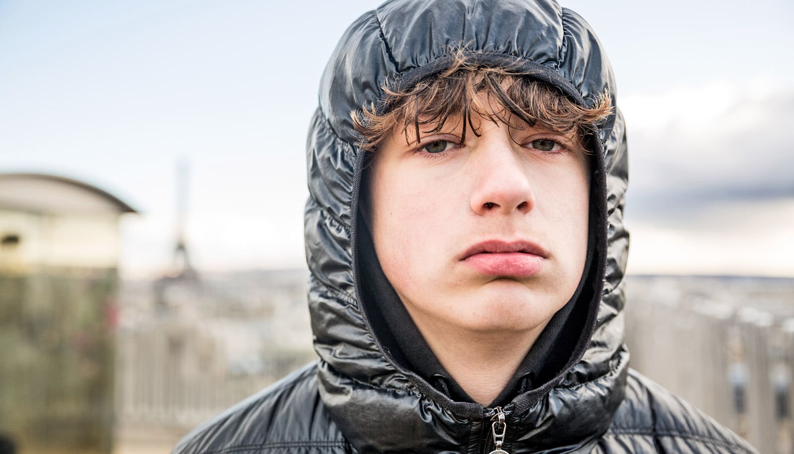 teenagers ansigt ser elendigt ud i sort parka med hætte