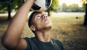 teen looks up while balancing ball on forehead