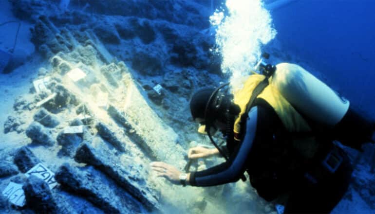 diver inspects objects on sea floor