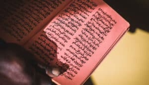 hand holds red pages with writing in Ajami