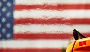 exhaust from yellow vehicle ripples the air in front of US flag