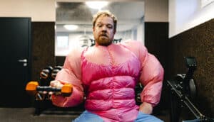 guy in pink bodybuilder costume lifts dumbbell