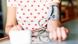 A woman checks her blood pressure with an at-home arm cuff device.