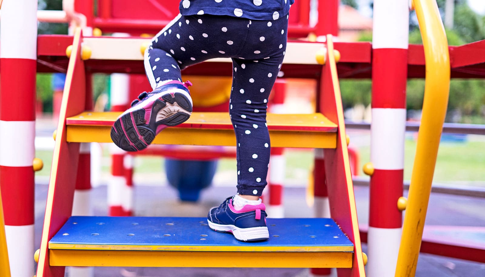 A young girl walks up playground stairs.