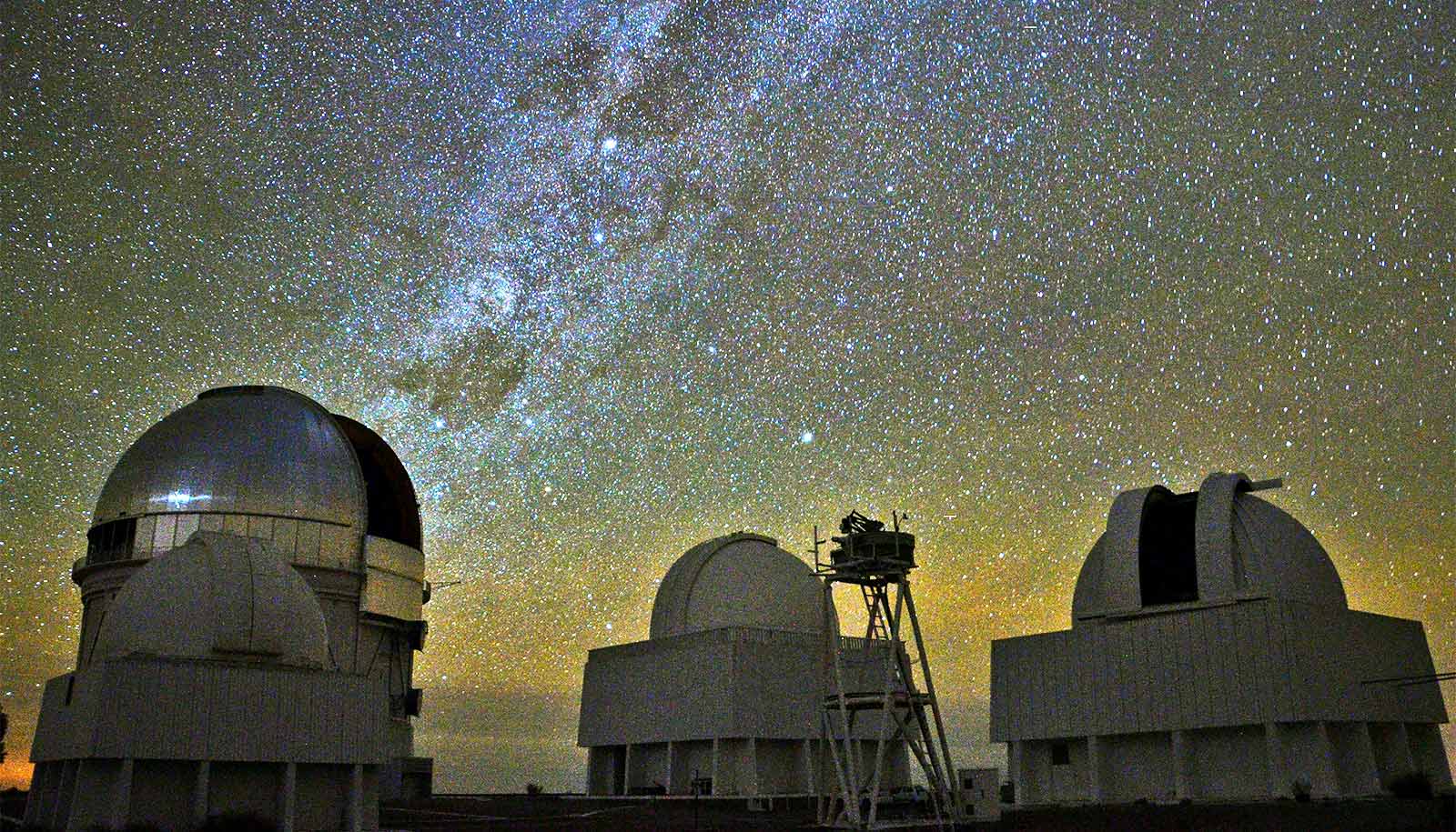Telescopes point up at the starry night sky.