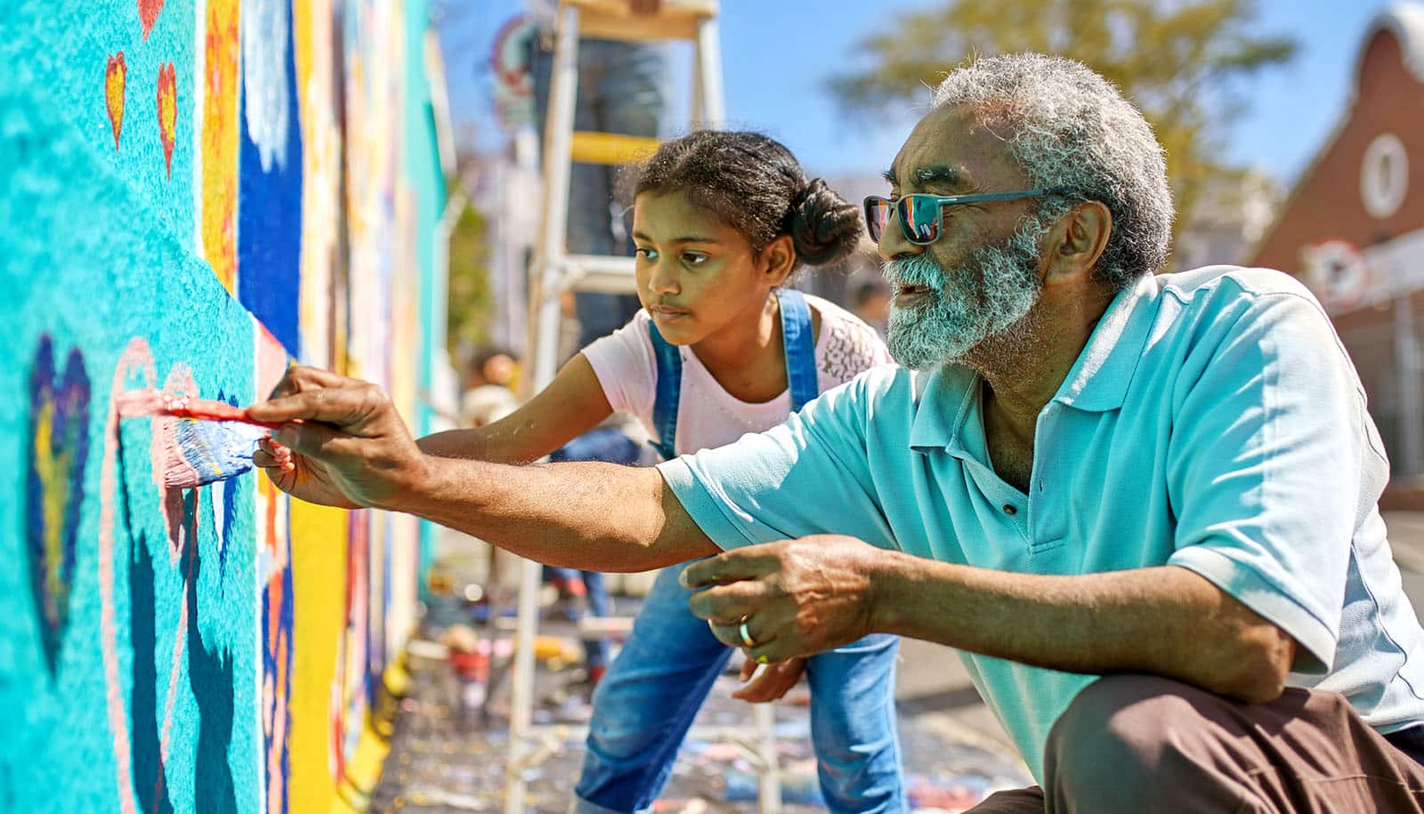 older adult and child paint mural outdoors