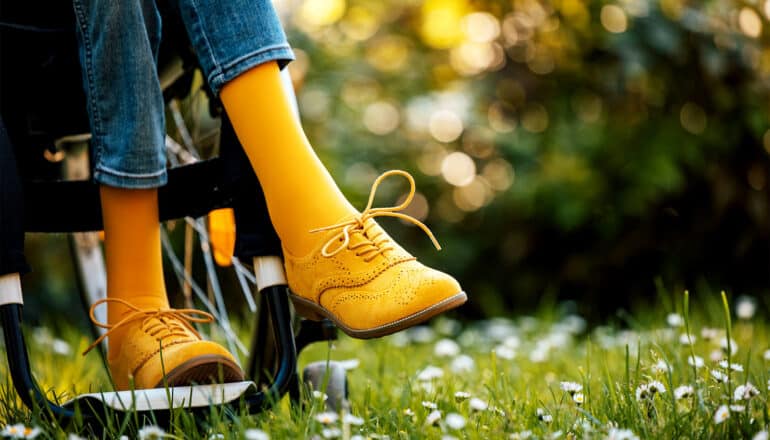 A person in a wheelchair wears bright yellow socks and dress shoes.