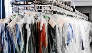 Dry cleaning in plastic on a movable clothing rack.