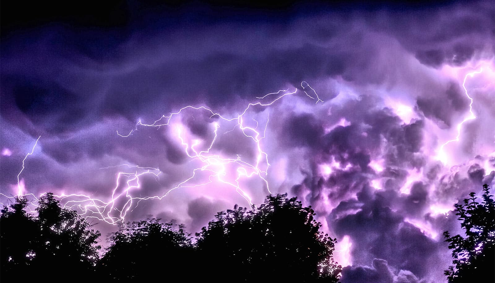 A dark and cloudy sky filled with purple lightning.