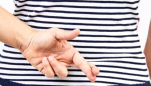 A person crosses their fingers behind their back.