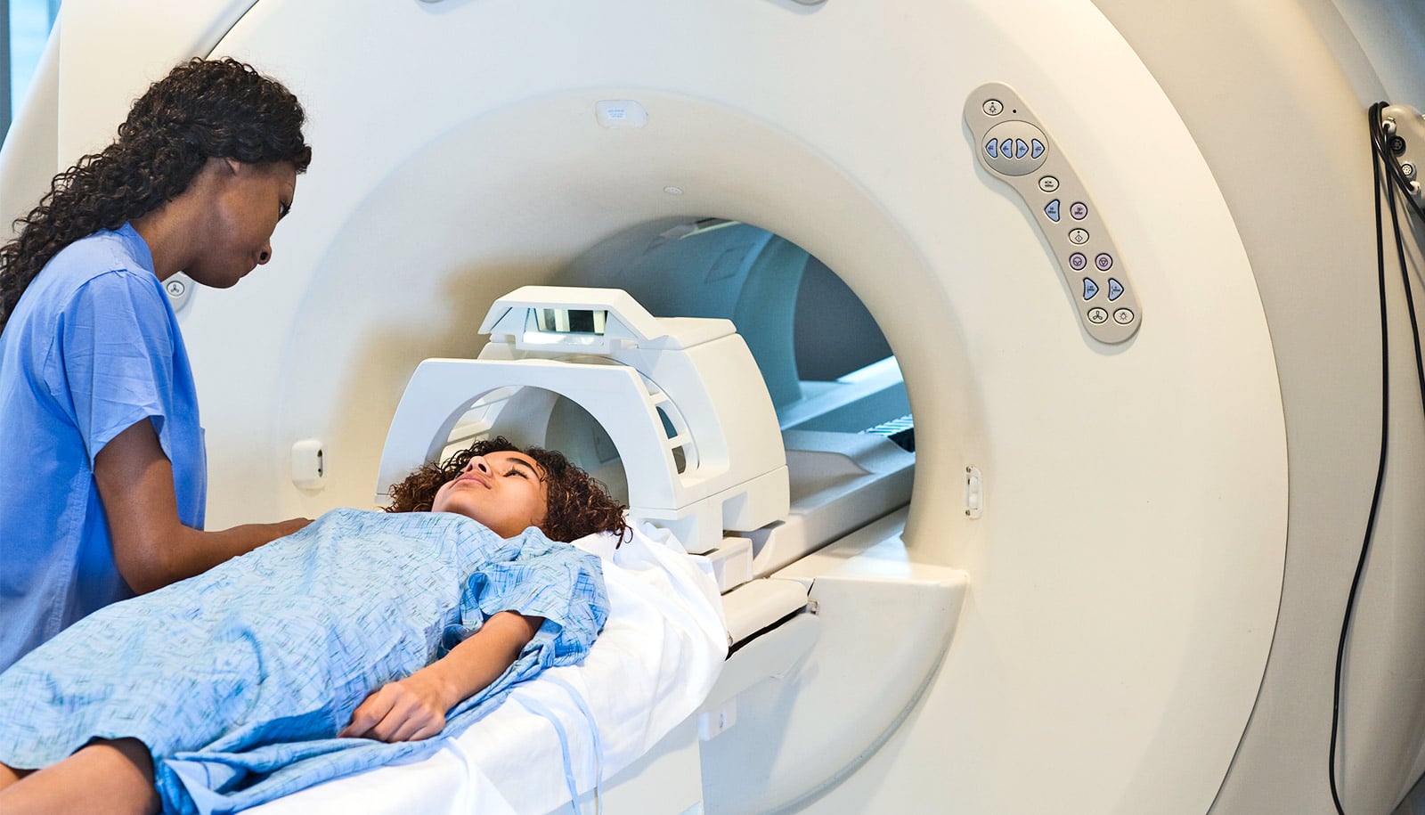 A health care worker helps a child waiting for an MRI scan.