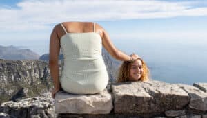 trick pose suggests person sits on ledge holding head beside them