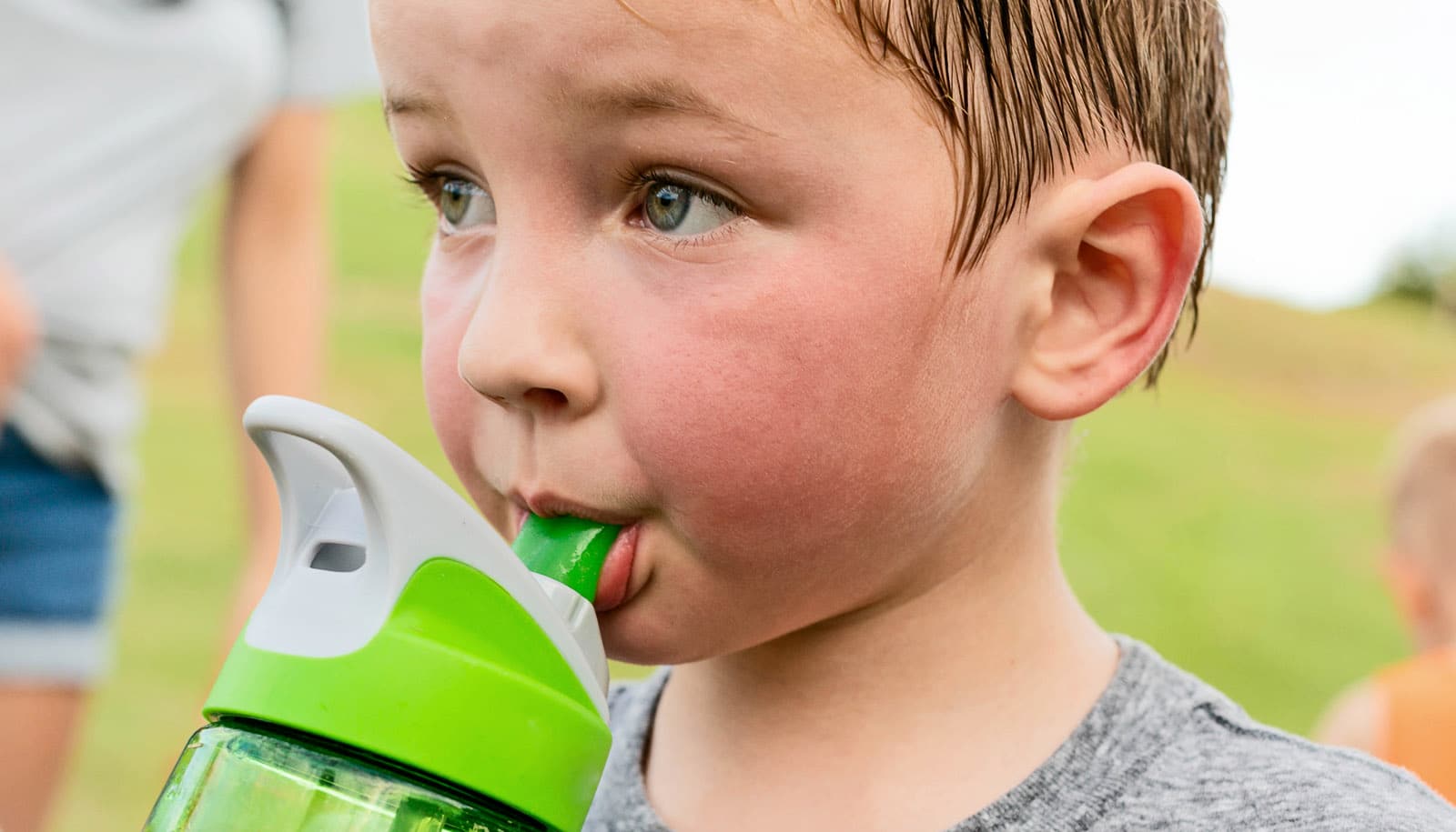 preschooler exercises outside, drinks water while sweaty