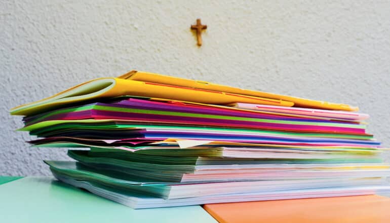 colorful folders and paperwork, cross on the wall behind