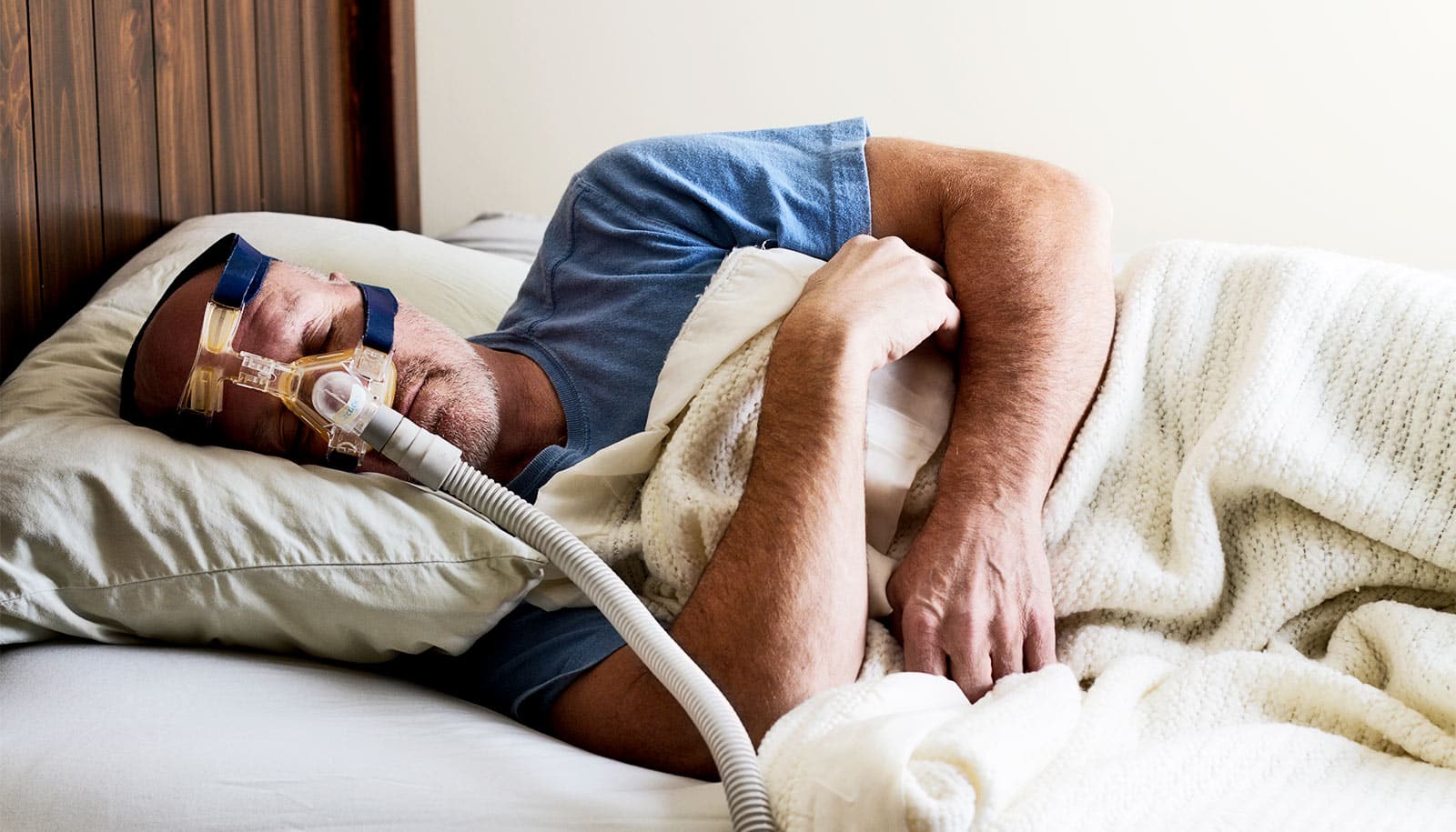 A man sleeps with a CPAP machine mask on his face.