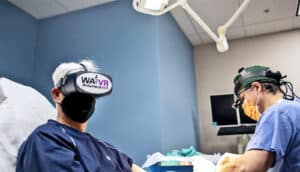 A person wears a virtual reality headset while getting surgery on their hand.