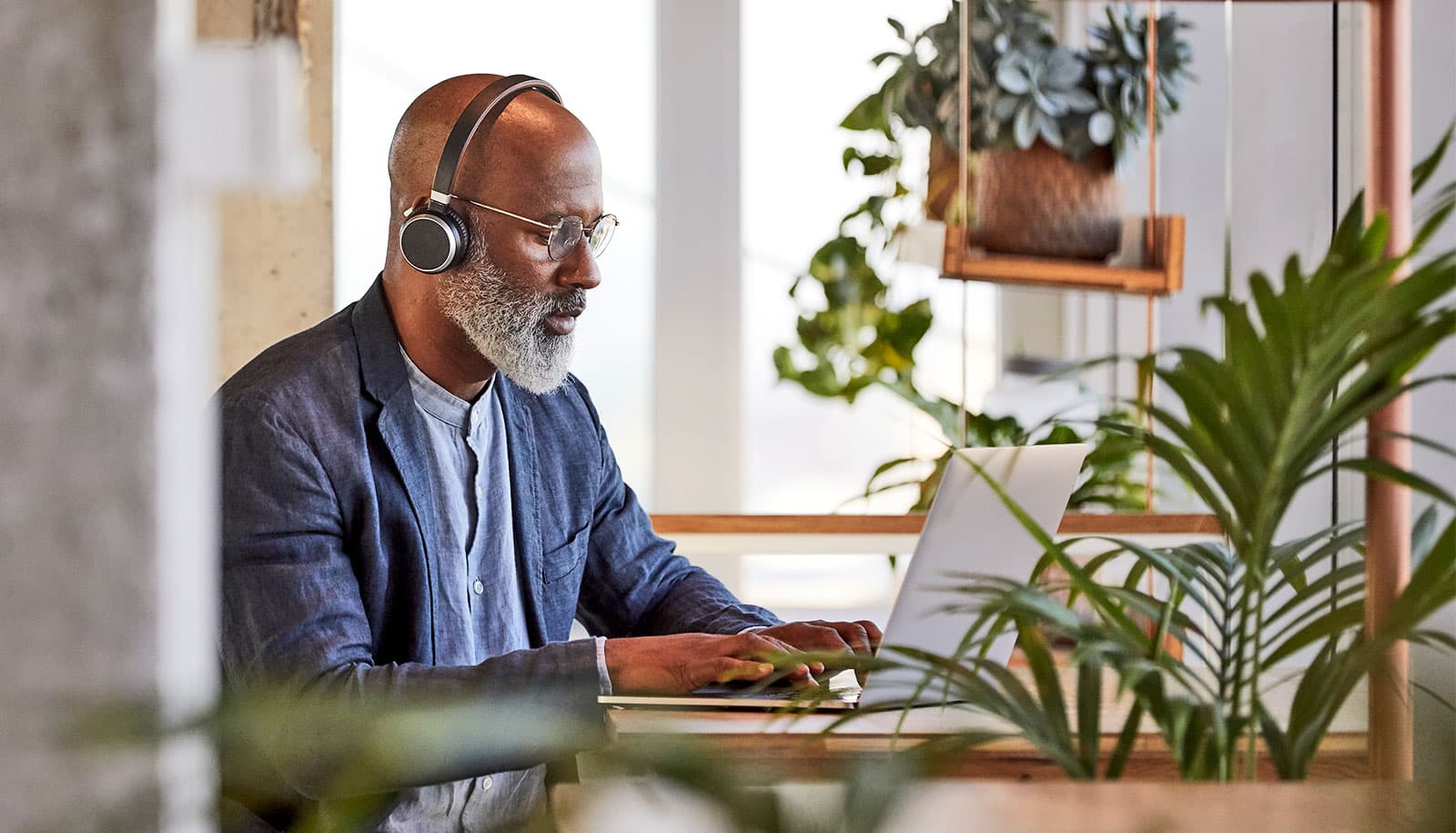 En mand arbejder på en bærbar computer ved et skrivebord i sit hjem.