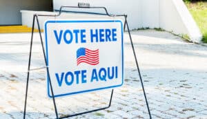 sign with US flag says "vote here" and "vote aqui"
