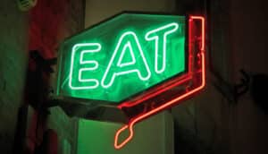 A neon signs reads "Eat" in green lettering.