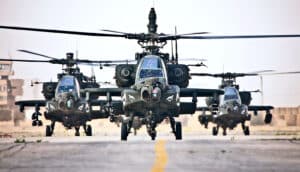 Three military helicopters landed on a road.