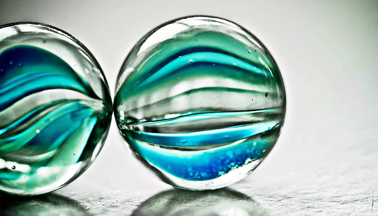 Two glass marbles on a metallic surface.