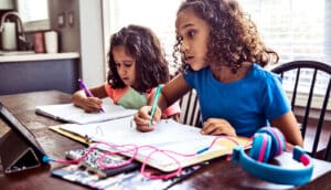 two kids at table with notebooks and pencils