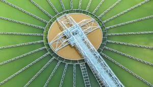 aerial view of wastewater treatment plant: blue metal arm over green water