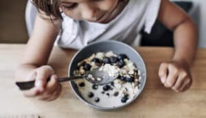 high-angle view of child eating cereal with berries