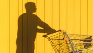 person's shadow appears to put shopping cart against yellow wall