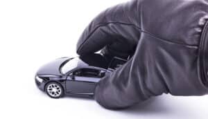 A gloved hand picks up a toy car on a white background.