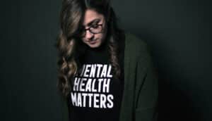 dark photo of person looking down and wearing shirt saying "mental health matters"