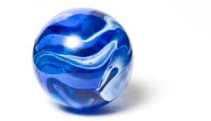 A blue marble sitting on a white surface.