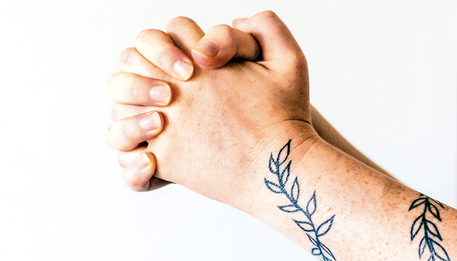 Hands clasped together against a white background.
