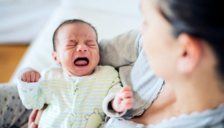 A newborn baby crying while being held.