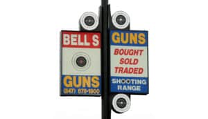 sign says "bells guns / guns bought sold traded / shooting range"