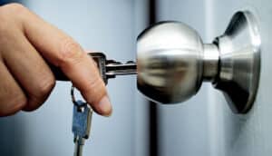 A woman unlocks a door with a key.