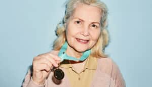 older adult holds up prize medal around neck