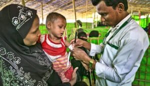 A health worker checks a young boy for signs of malnutrition.