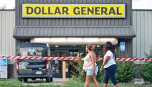 two people walk pass Dollar General store with police tape in front