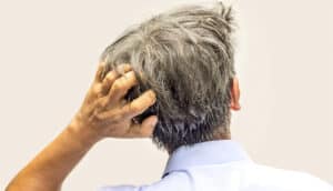 A man scratches the back of his head.