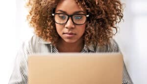 A young woman looks down at a laptop computer.