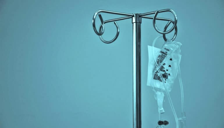 An IV bag hanging on a metal rack.