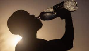 person in silhouette drinks from water bottle