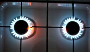 Two stove burners emit flames with no cookware over them.