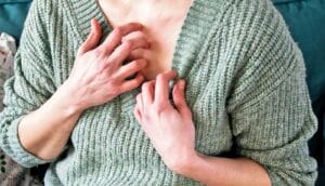 A woman scratches at her chest.
