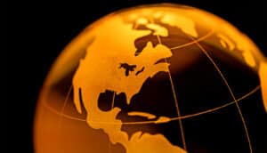 A golden-colored model of Earth against a black background.