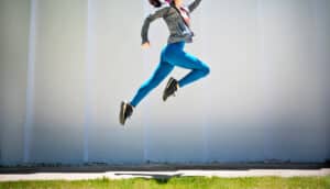 A woman leaps into the air in a dramatic way, jumping higher than is actually possible.