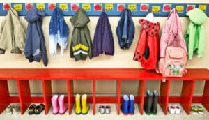 Children's coats and boots against a wall in a child care center.